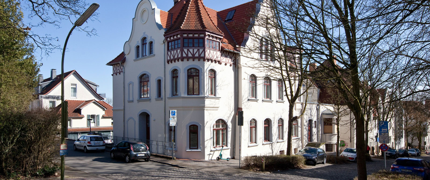 Vila von 1899 mit Rundgeibel links und Stufengiebel rechts, dazwischen ein kleiner Turm. Ober ist rot gestrichenes Fachwerk zu sehen